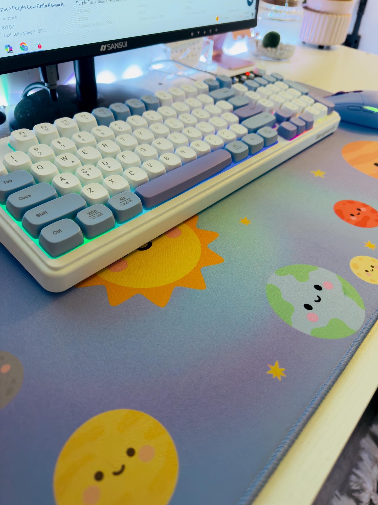 Keyboard on a desk with a colorful mouse pad featuring cartoon suns and planets.