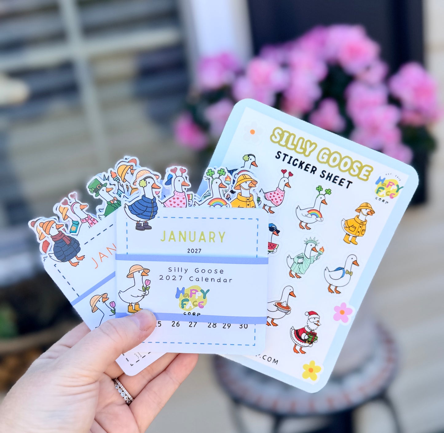Hand holding a 'Silly Goose' sticker sheet with cartoon characters and calendar design.