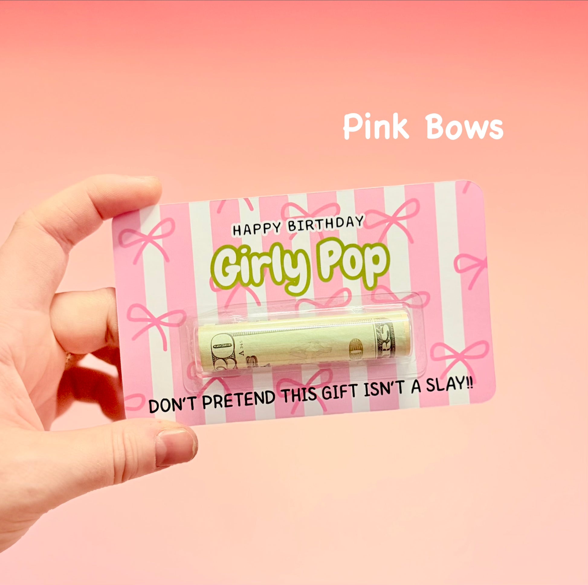 Hand holding a 'Happy Birthday Girly Pop' product with pink packaging on a pink background