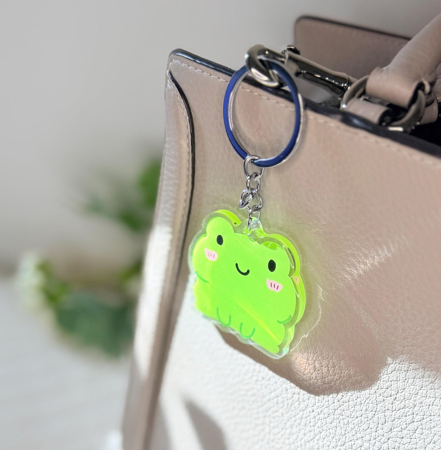The green frog keychain displayed on a purse
