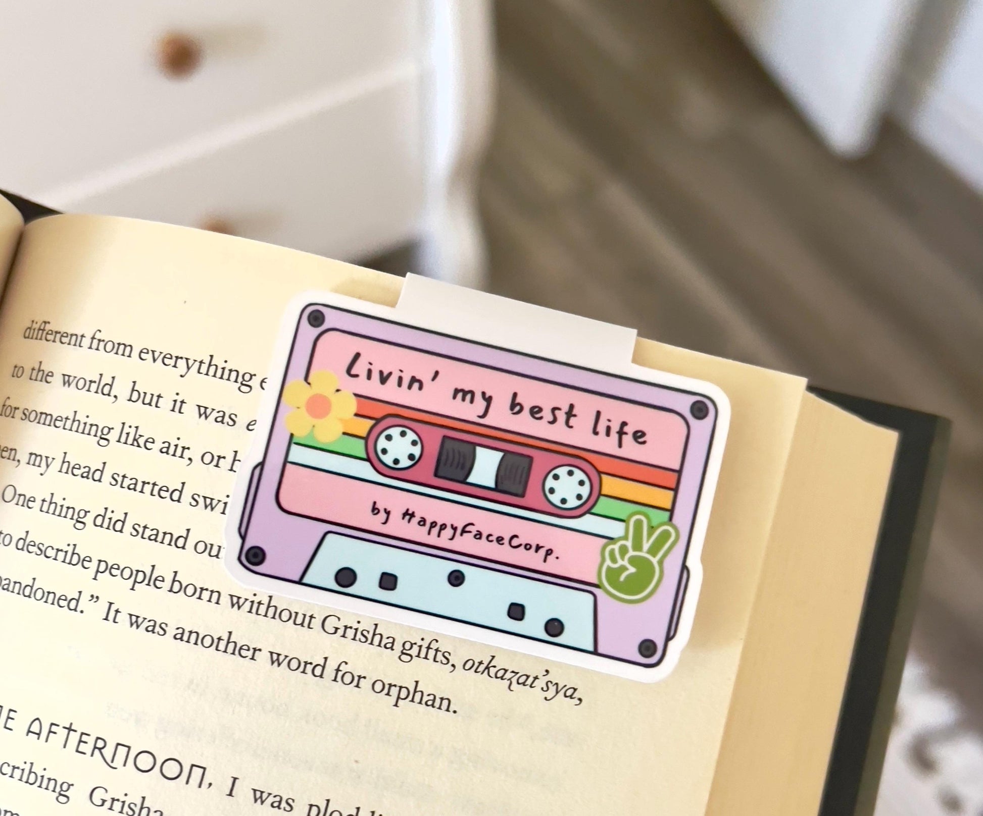 A magnetic bookmark of a colorful, cartoon style retro cassette tape that says livin my best life