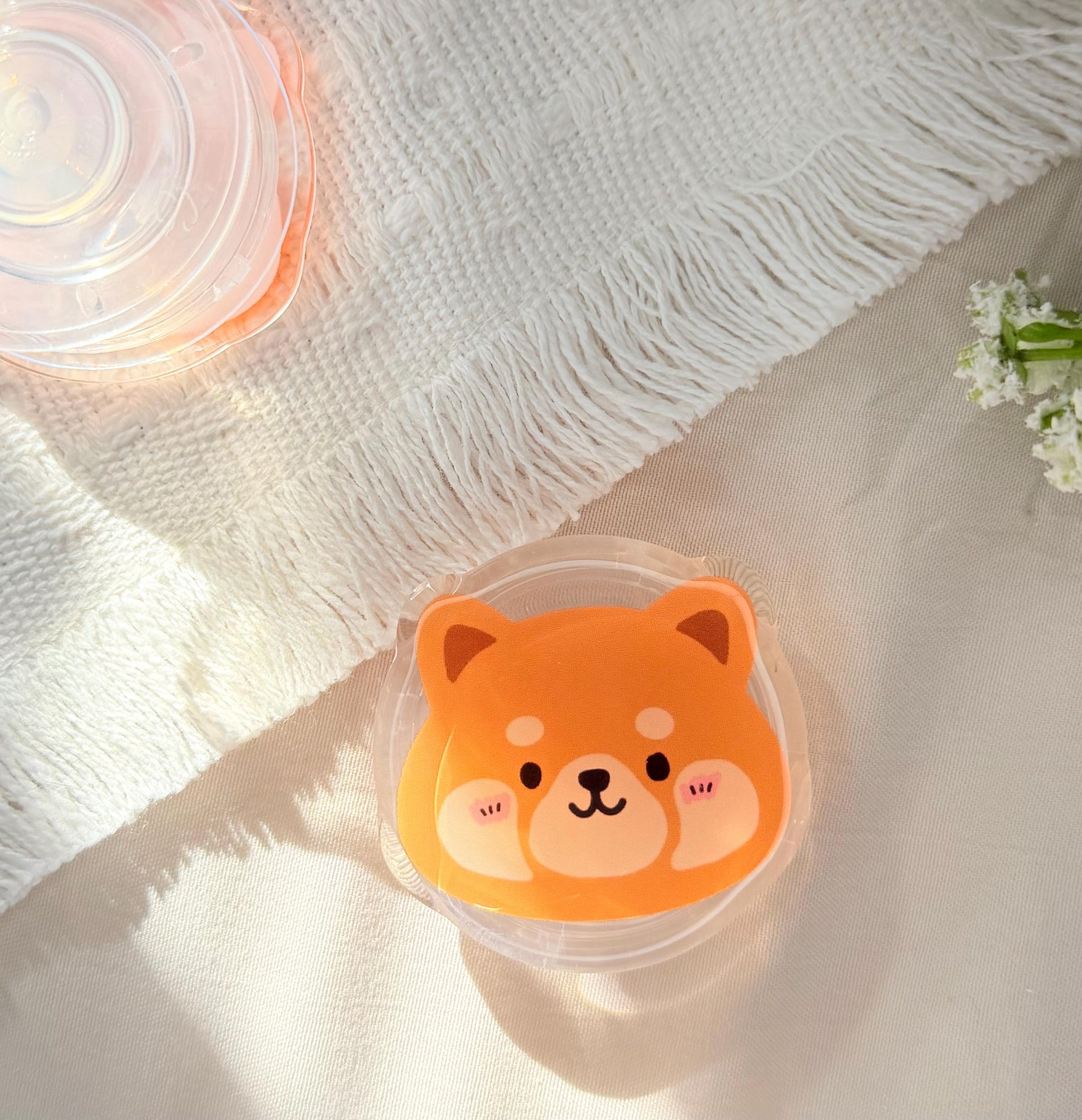 An acrylic phone grip of a Kawaii style red panda face