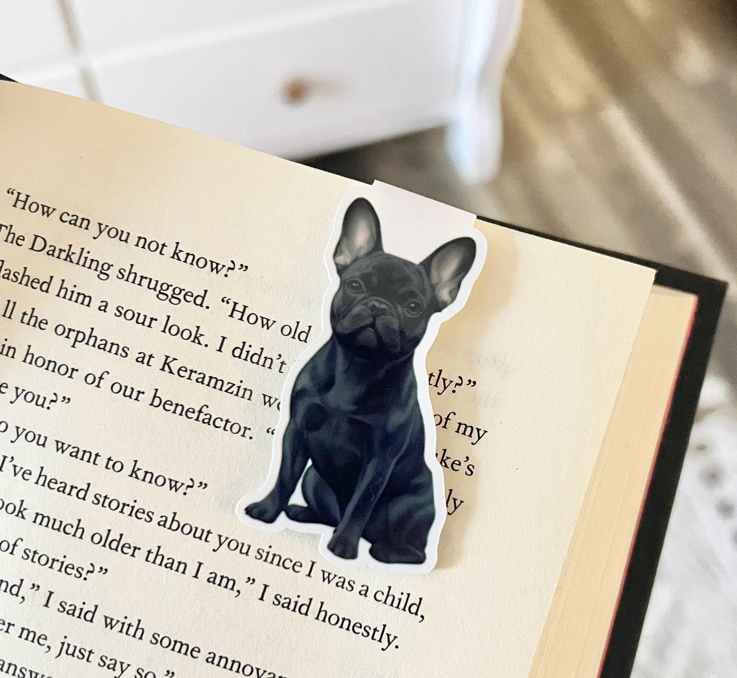 A magnetic bookmark have a semi realistic, cartoon style dark gray Frenchie dog