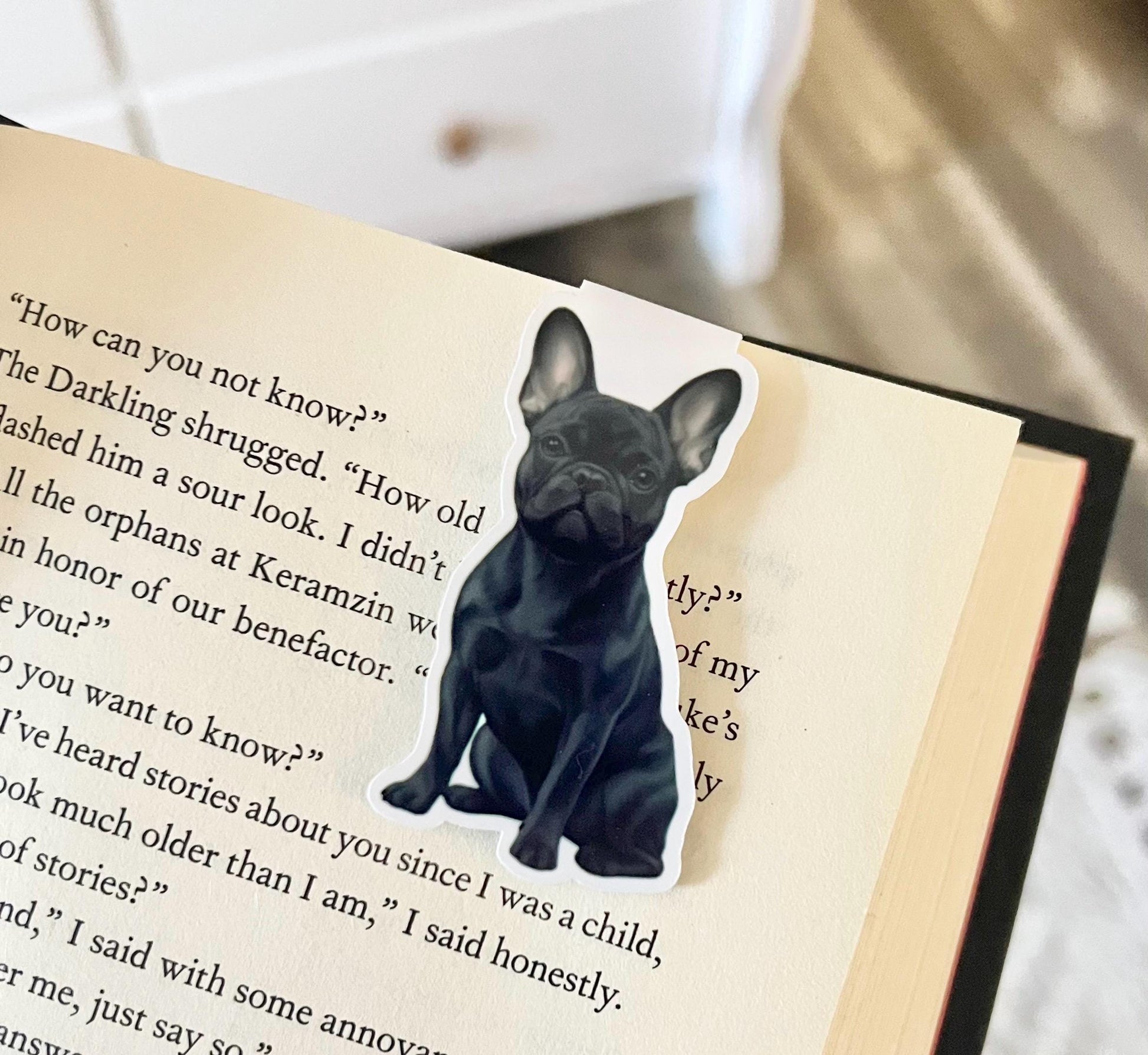 A magnetic bookmark have a semi realistic, cartoon style dark gray Frenchie dog