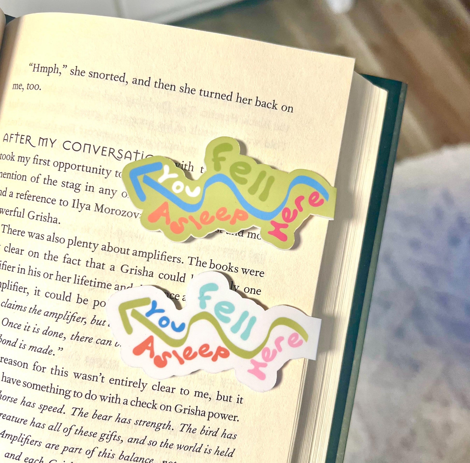 A magnetic bookmark set of two bookmarks one is white and says you fell asleep here with an arrow in the other is lime green that says the same thing with an arrow