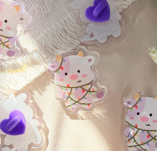 A cute acrylic pen of a Kawaii style purple spotted cow wrapped in Christmas lights