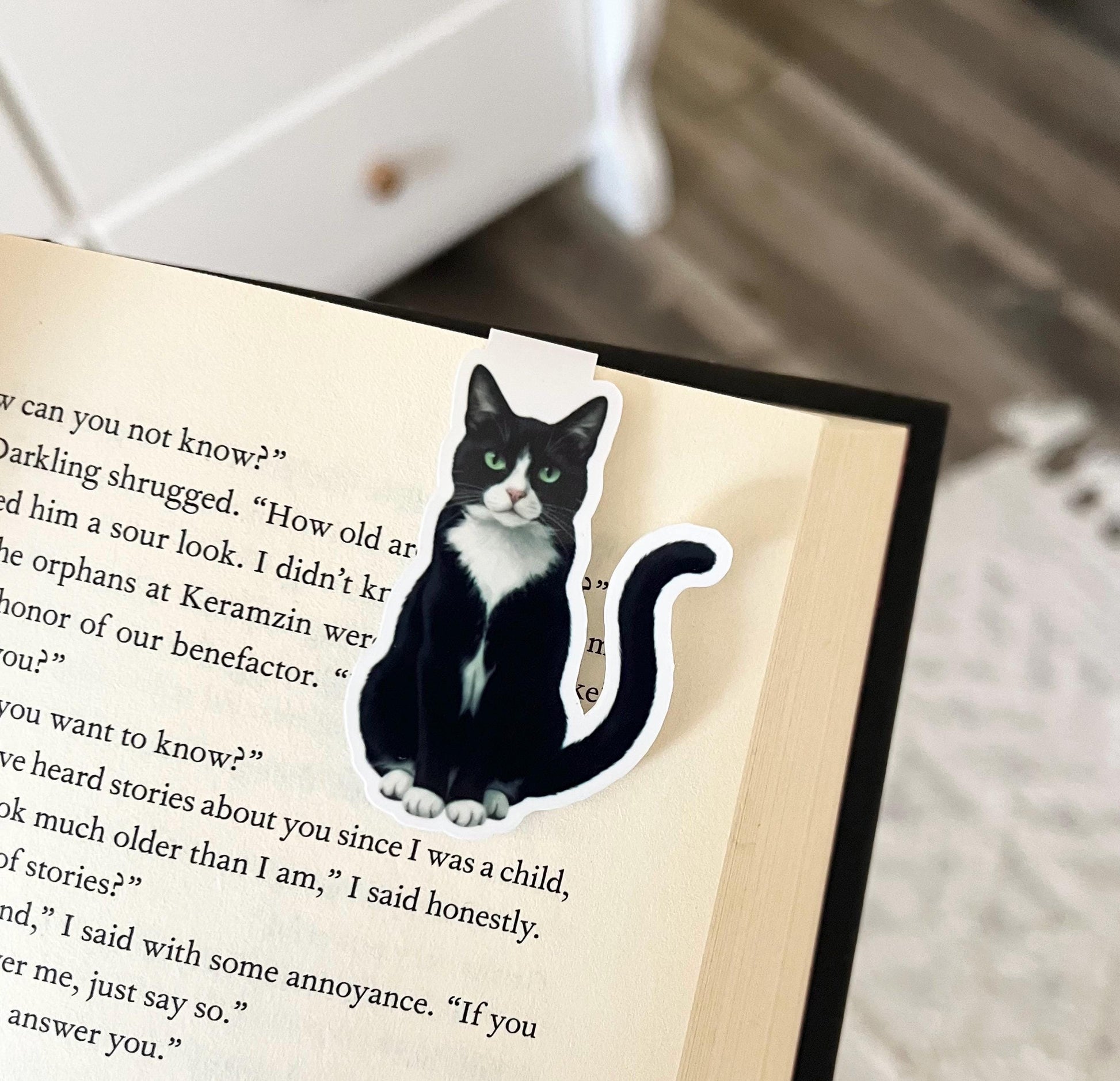 A magnetic bookmark of a semi realistic, cartoon style black-and-white tuxedo cat