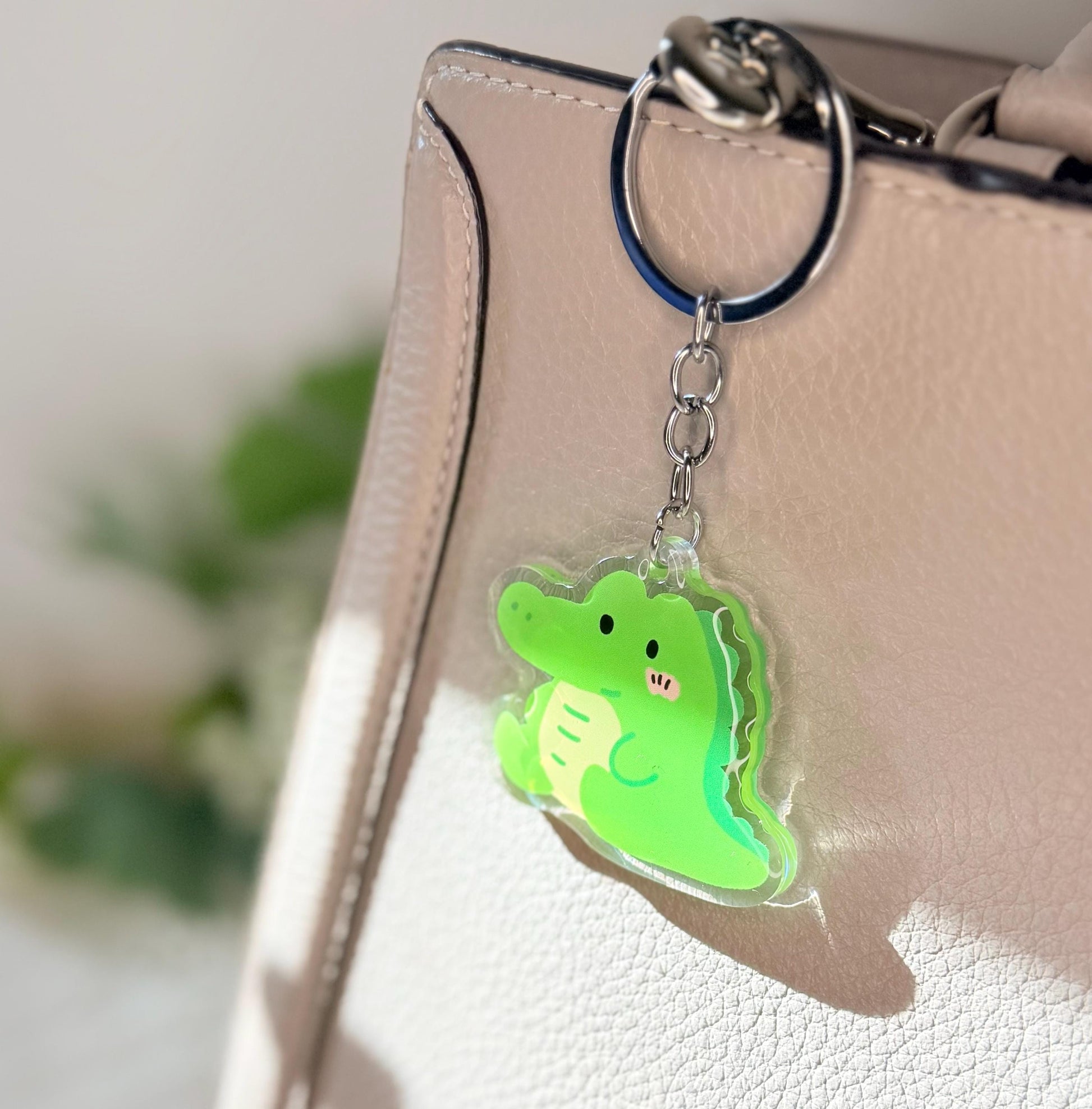 The green alligator keychain displayed on a purse