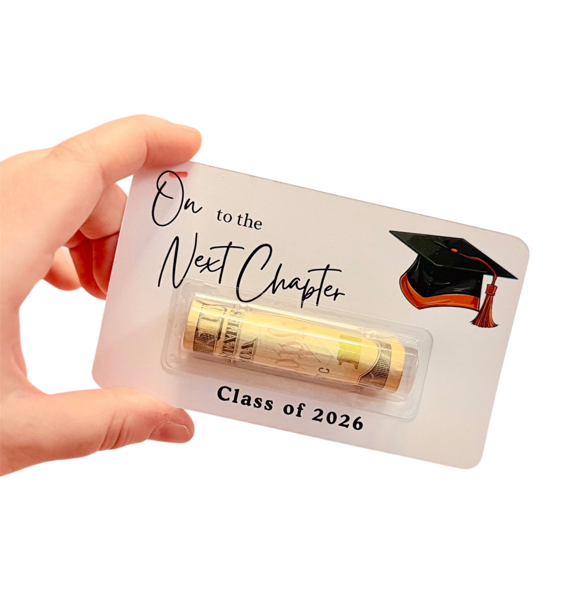Hand holding a card 'On to the Next Chapter Class of 2026' text, featuring a graduation cap icon.