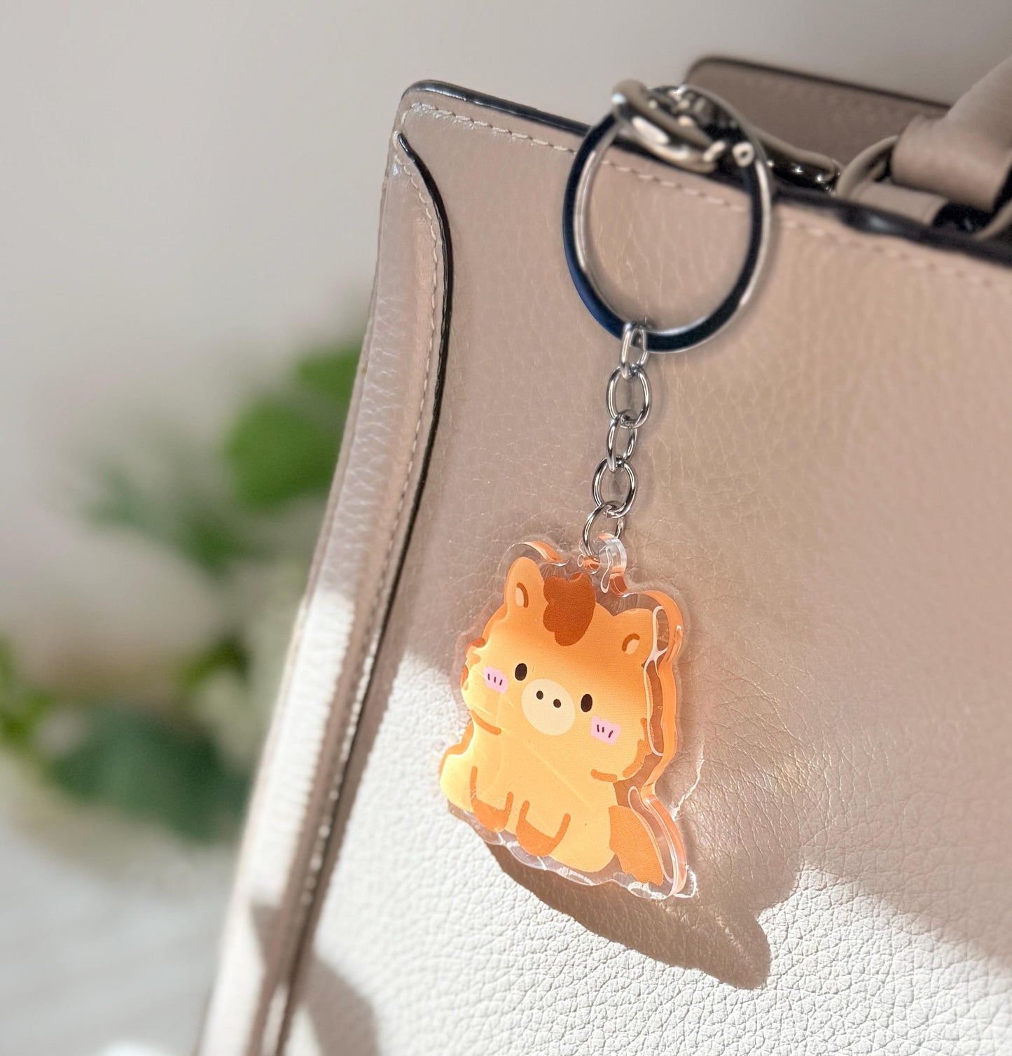 The brown horse keychain displayed on a purse