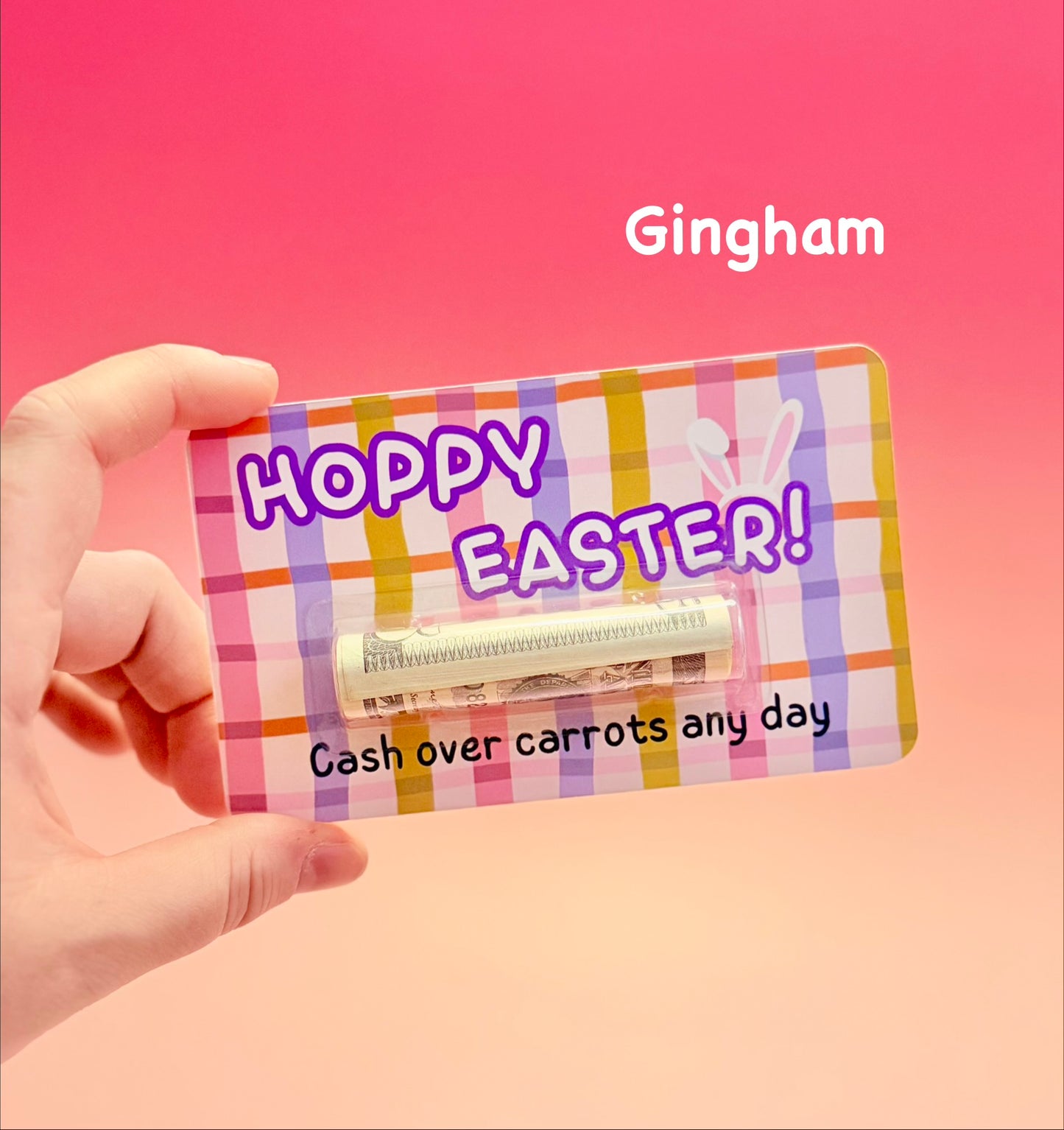 Gingham-patterned Easter card with 'Happy Easter!' text held by a hand against a pink background.