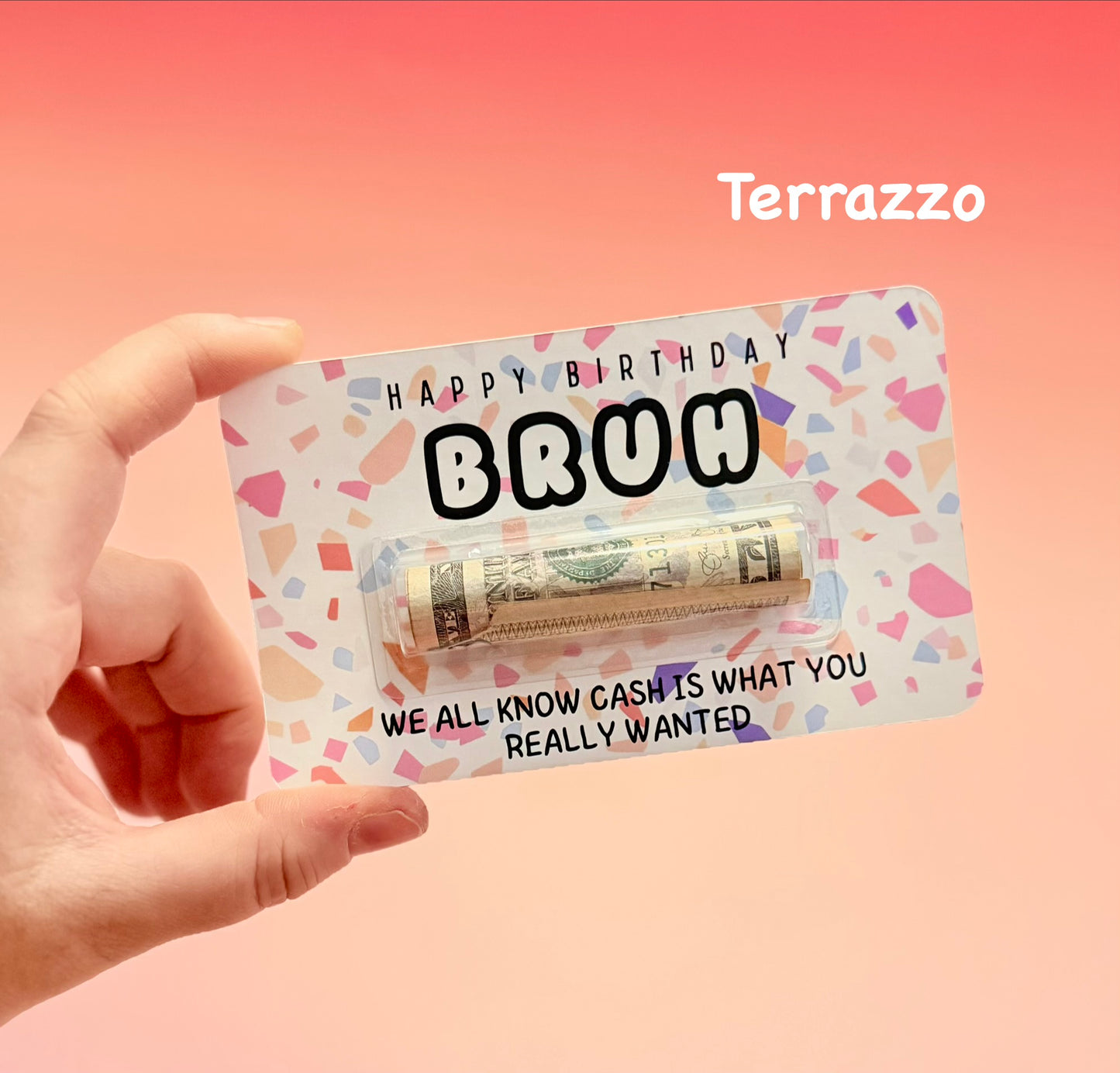 Hand holding a birthday card with money and 'Terrazzo' branding on a pink background