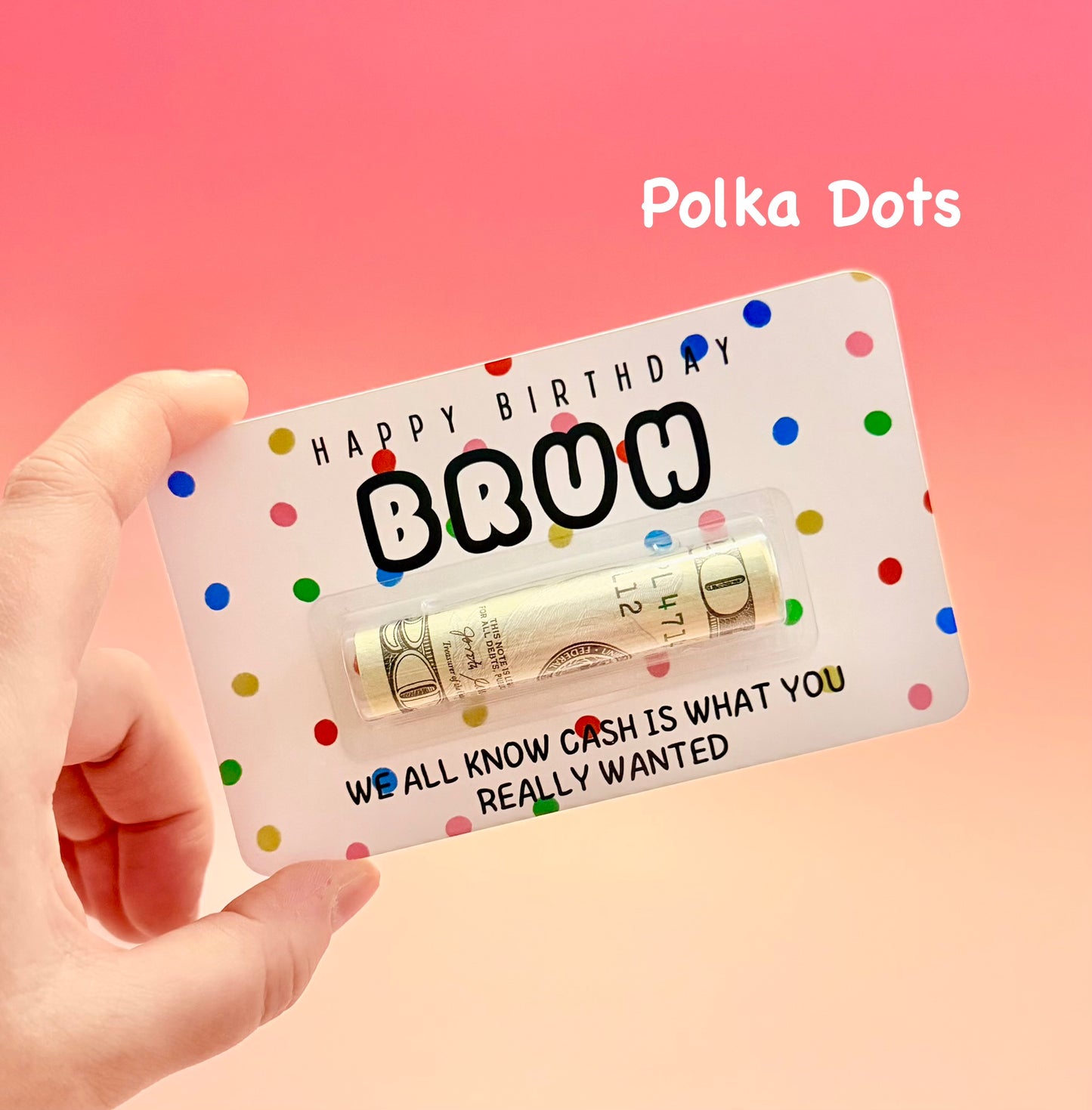 Gift card with polka dots and rolled cash, held by a hand against a pink background.