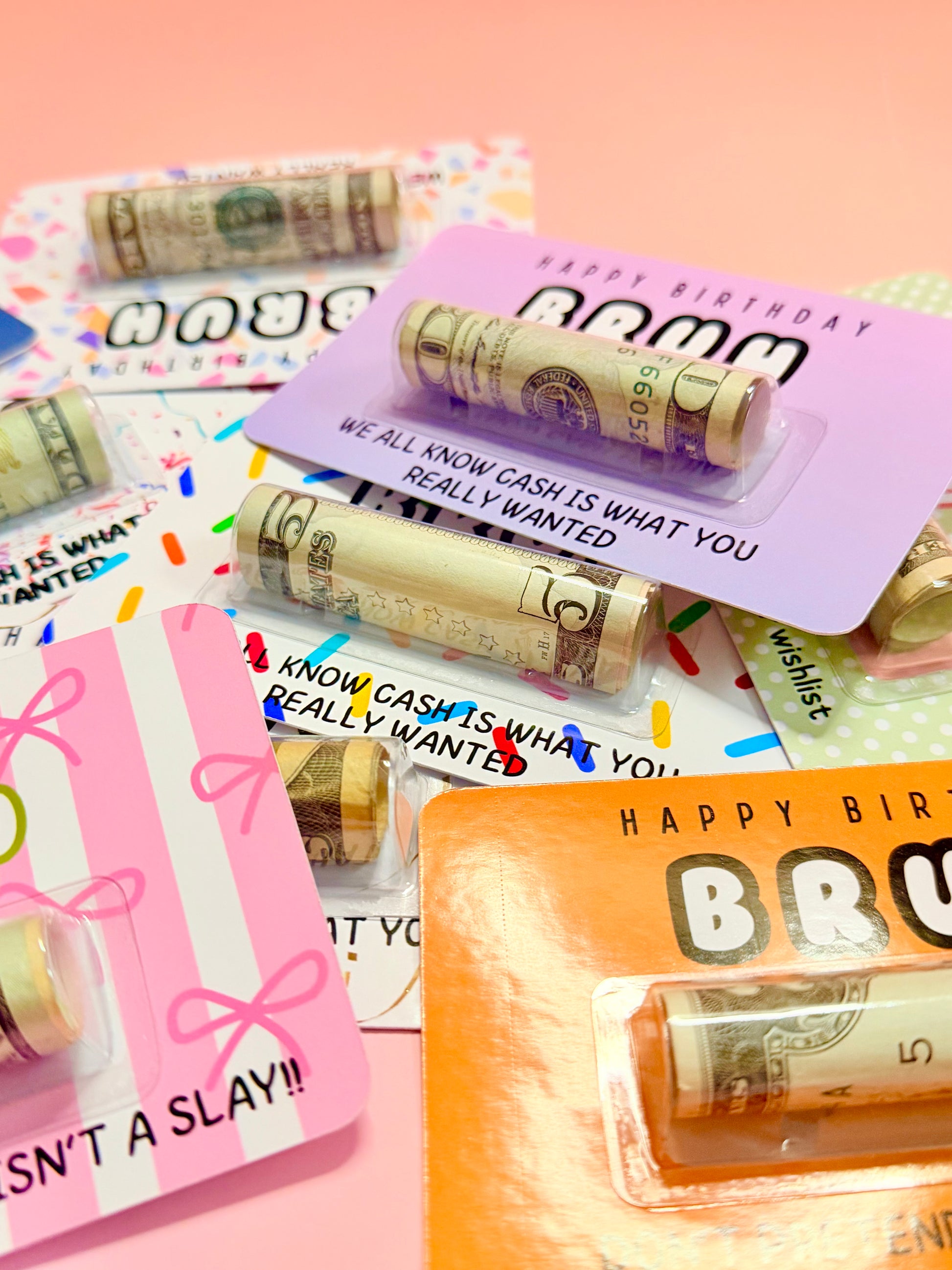 Rolls of cash on personalized birthday cards with text on a pink background