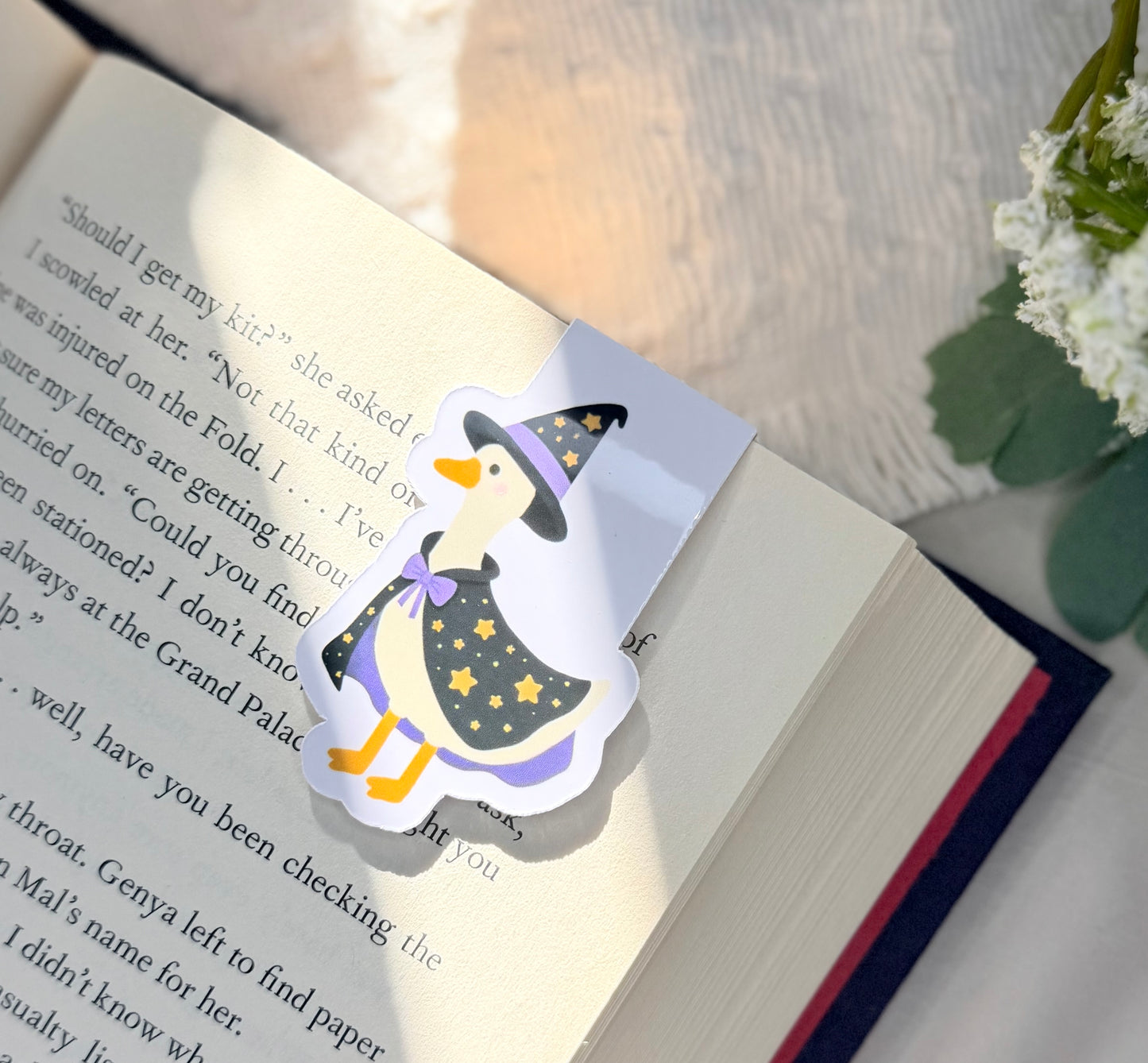 A magnetic bookmark of a silly goose wearing a black and purple star patterned magicians outfit