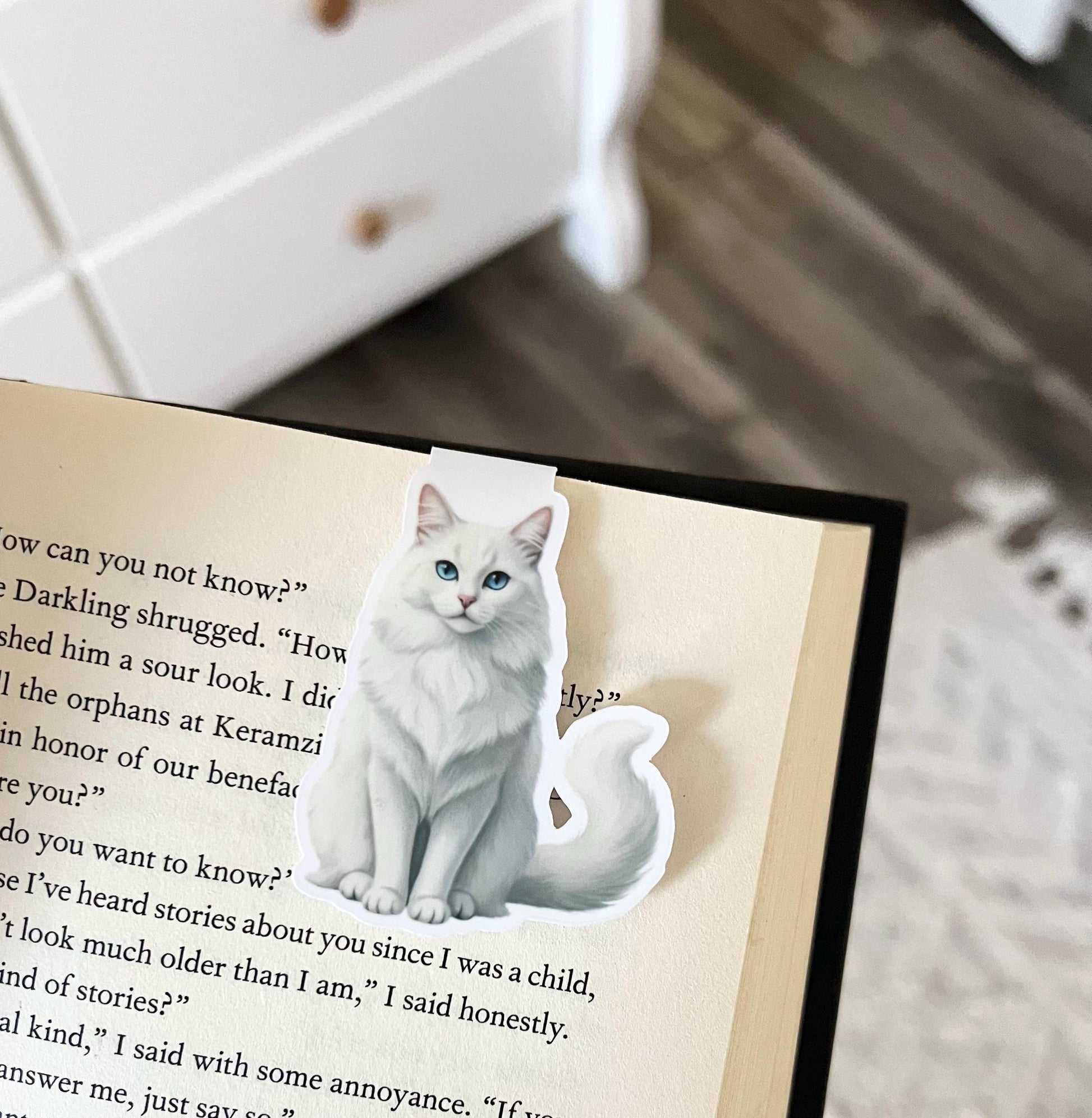 A magnetic bookmark of a semi realistic, cartoon style long-haired, white cat