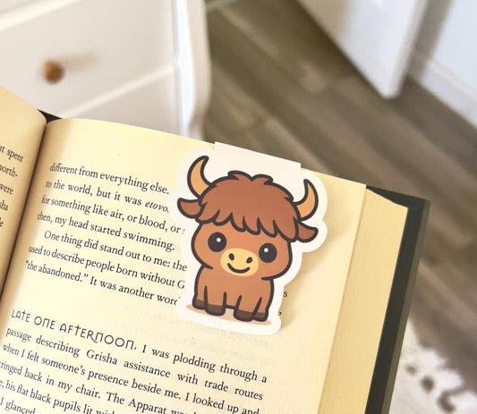 A magnetic bookmark of a cartoon style highland cow with a giant head