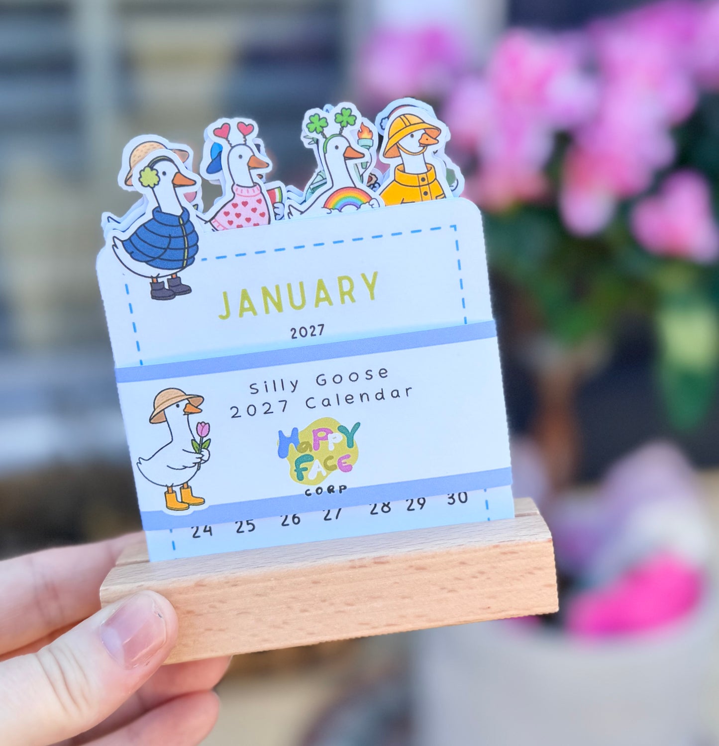 Calendar with cartoon geese design held by a hand, with a blurred background