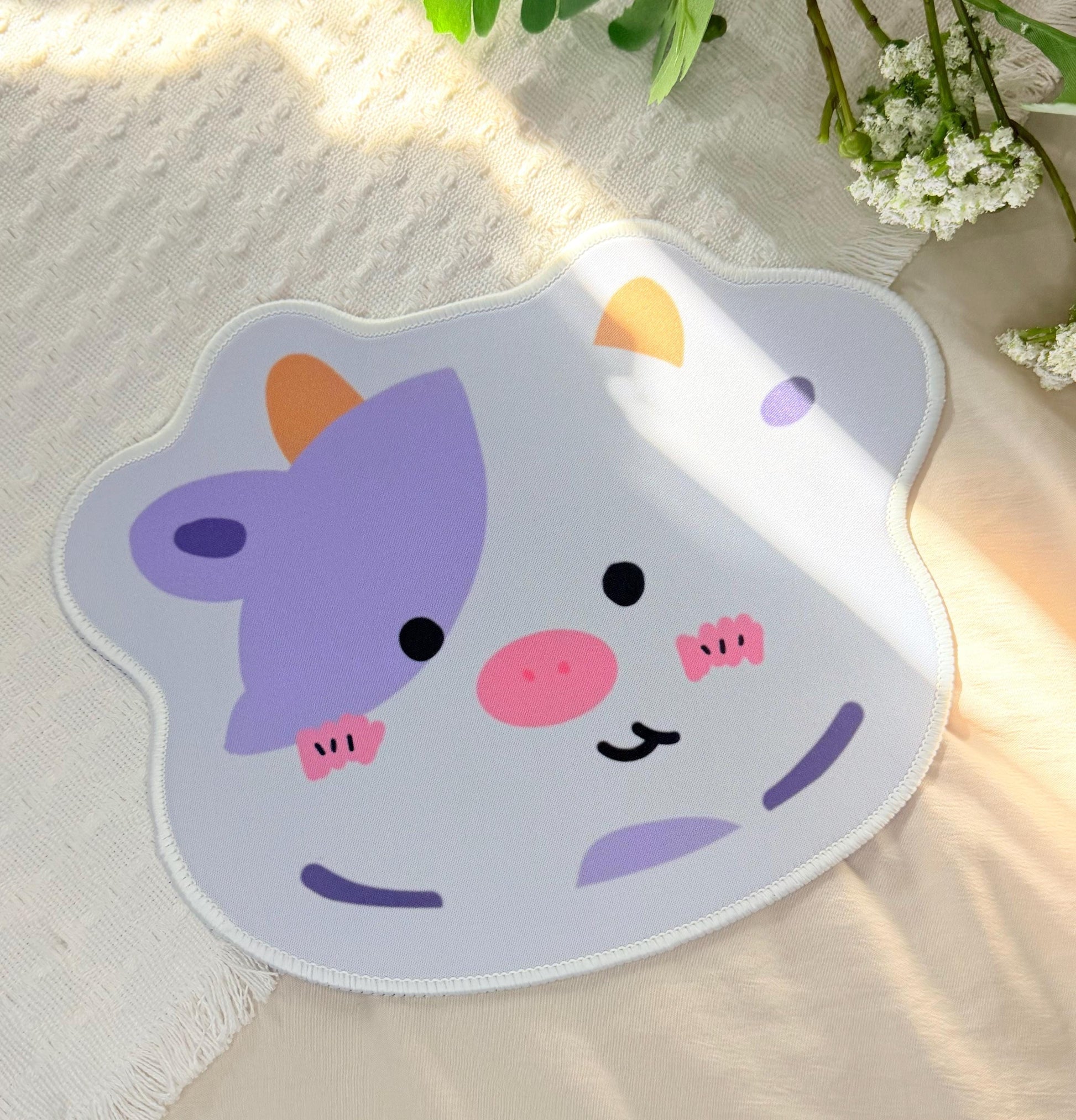 
A mouse pad of a white and purple spotted Kawaii cow face