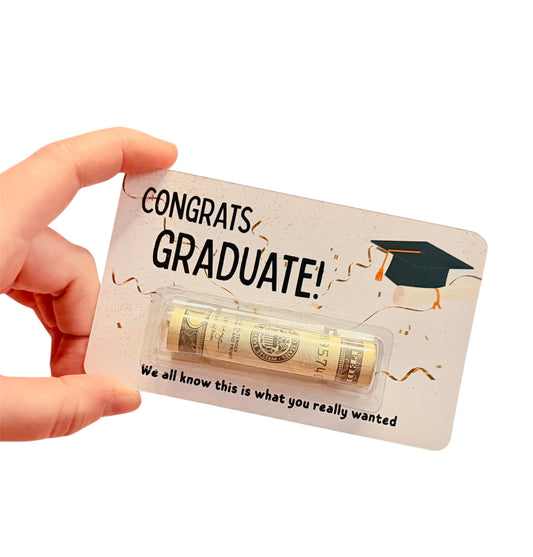 Hand holding a 'Congrats Graduate!' card with a small tube of cash