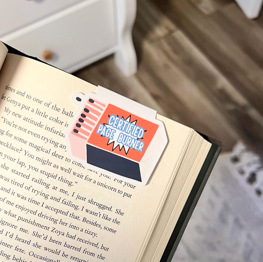 A magnetic bookmark of an orange and blue box of matches in a cartoon style that says certified page burner