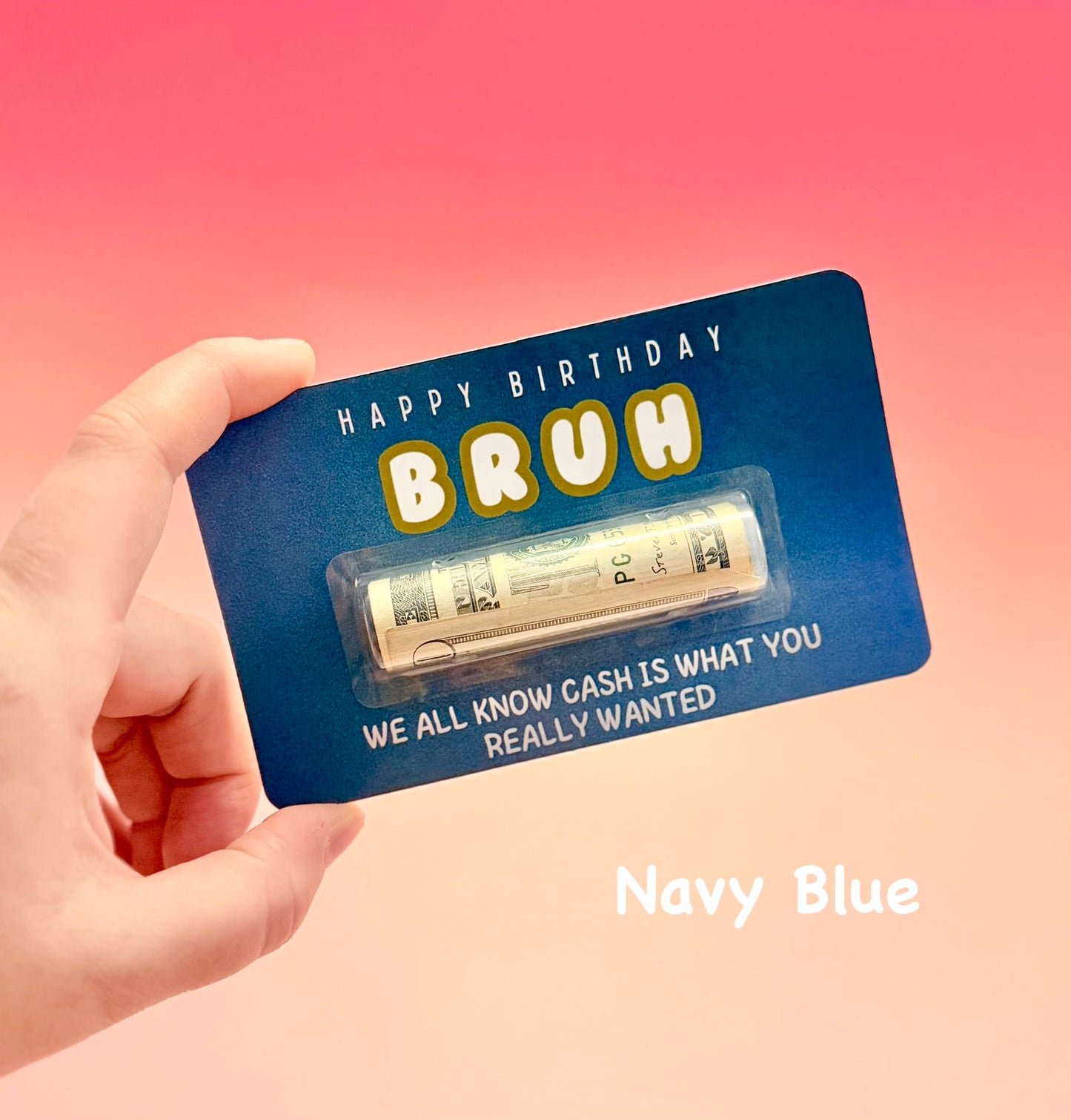 Navy blue card with 'Happy Birthday Bruh' text and a small amount of cash, held by a hand against a pink background.