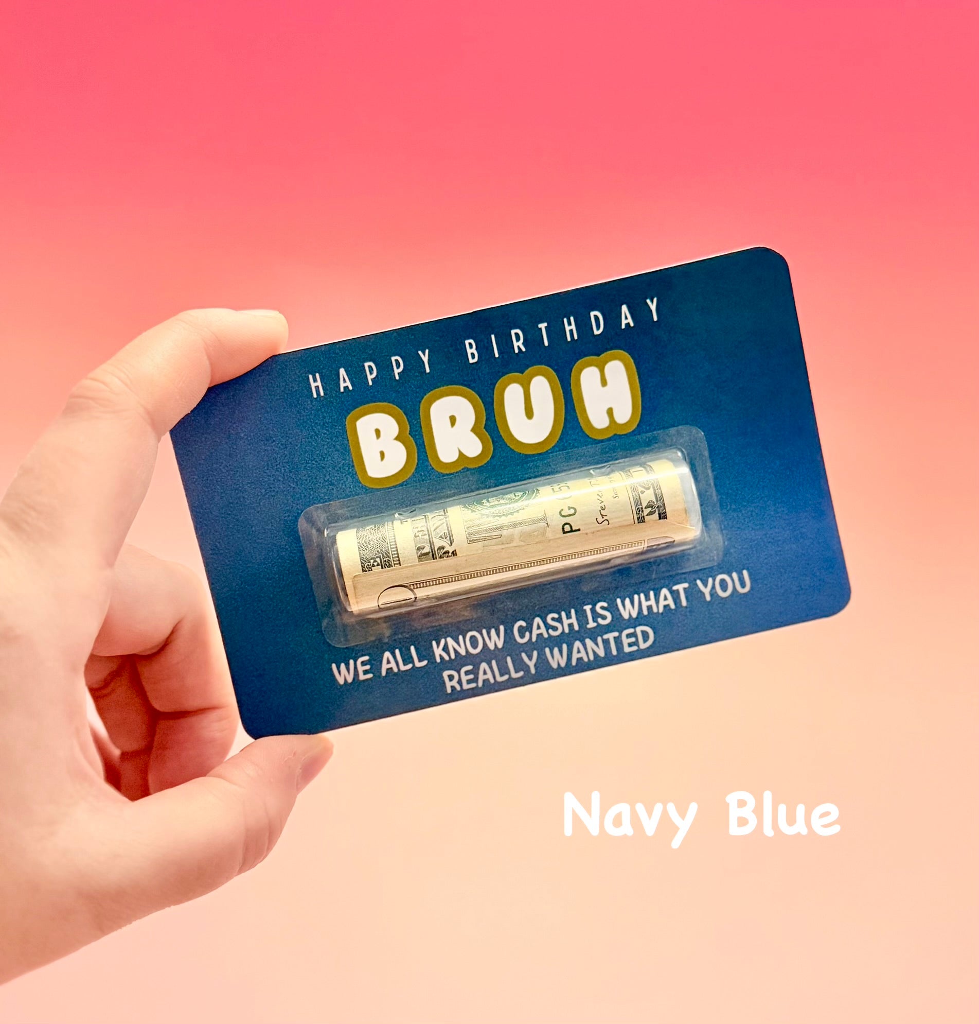 Navy blue card with 'Happy Birthday Bruh' text and a small amount of cash, held by a hand against a pink background.