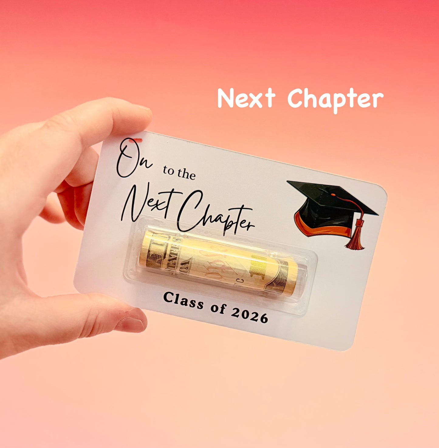 Hand holding a small gold capsule with a graduation cap on a pink background, labeled 'Next Chapter'.