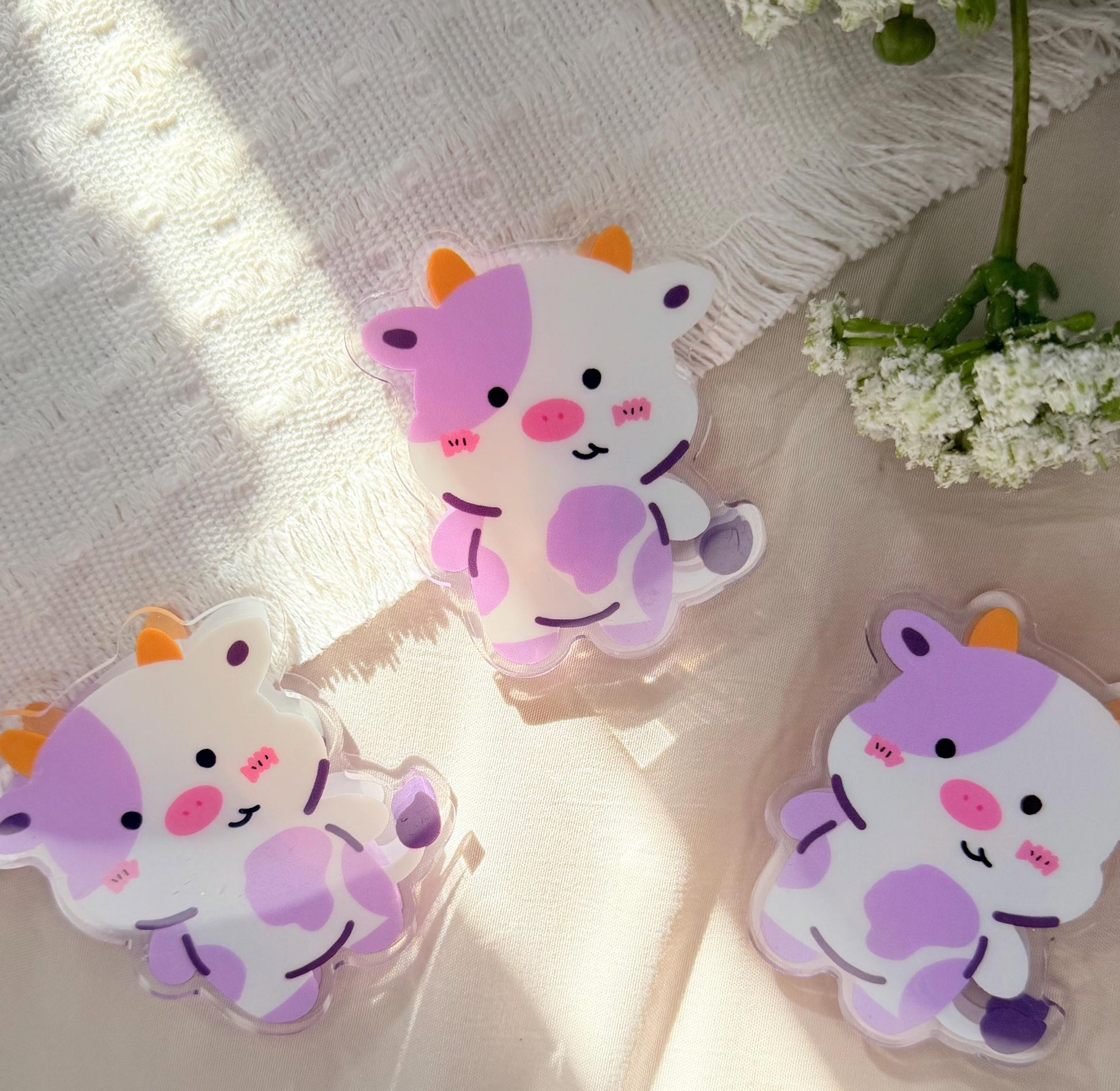 An acrylic chip clip/binder clip of a Kawaii style purple spotted cow